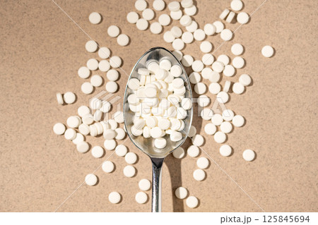 Sugar substitute, sweetener pills in a spoon, top view. Food supplement. Diabetic, over weight, health concept Sugar substitute, sweetener pills in a spoon, top view. Food supplement. Diabetic, over weight, health concept 125845694