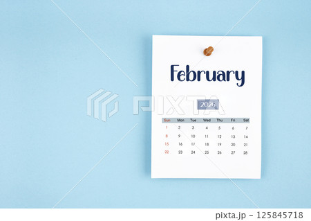 February 2026 calendar page with push pin on blue background. February 2026 calendar page with push pin on blue background. 125845718
