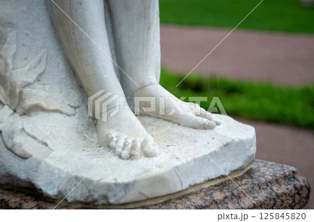 Close-up of marble sculpture feet in outdoor garden setting 125845820