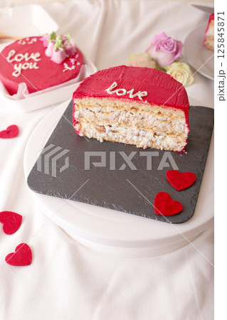 Red valentine's cake slice with heart decorations on slate plate 125845871