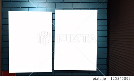 Two blank vertical posters on blue brick wall in dimly lit interior 125845895