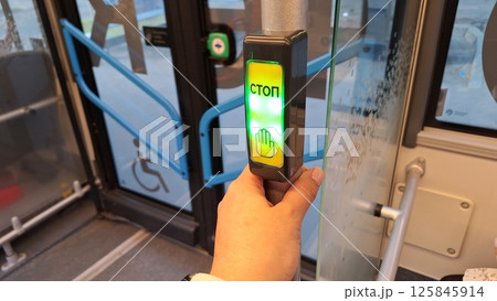 Moscow, Russia - April 26, 2025.Male hand pressing stop button on russian bus with accessibility features Moscow, Russia - April 26, 2025.Male hand pressing stop button on russian bus with accessibility features 125845914
