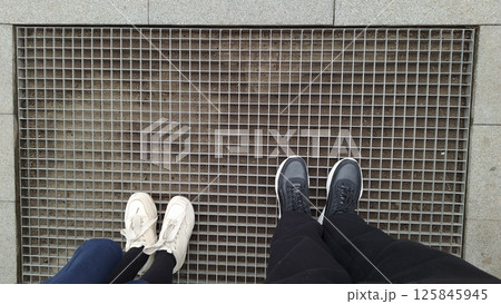 Two pairs of shoes of child and adult on metal grate 125845945