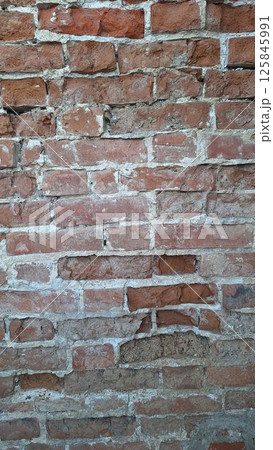 Old red brick wall with weathered texture and mortar detailing 125845991