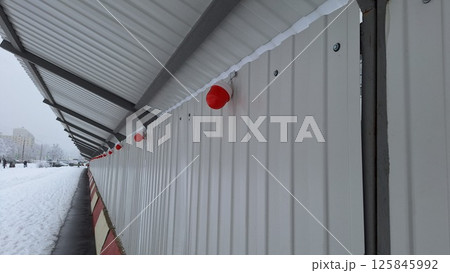 Snowy urban walkway with red lights and corrugated metal roof Snowy urban walkway with red lights and corrugated metal roof 125845992
