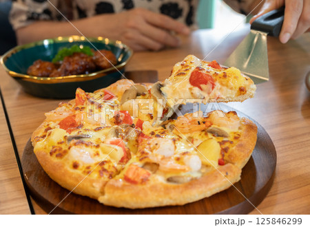 Someone using a pizza peel for separate a piece of pizza before eating. Someone using a pizza peel for separate a piece of pizza before eating. 125846299