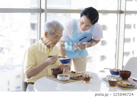介護イメージ　食事をするシニア男性と介護士 125846724