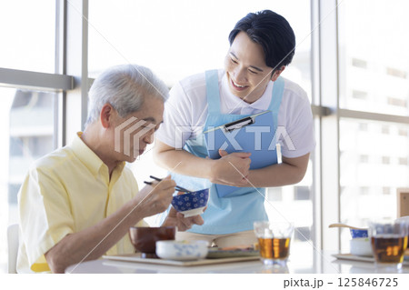 介護イメージ　食事をするシニア男性と介護士 125846725