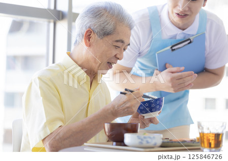 介護イメージ　食事をするシニア男性と介護士 125846726