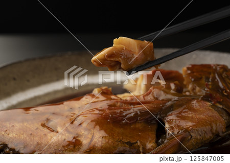 金目鯛の煮付けを箸で持ち上げる 125847005