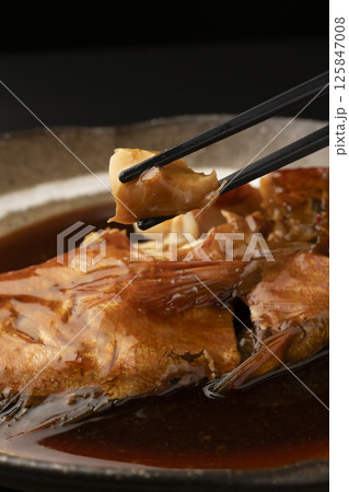 金目鯛の煮付けを箸で持ち上げる 125847008