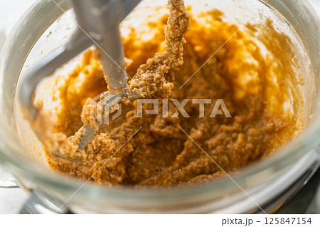Close-up view of the stand mixer blending the dough mixture to a smooth consistency, capturing the dough as it adheres to the mixing attachment in the Amber Gingerbread Cookie Dough process. The dough 125847154