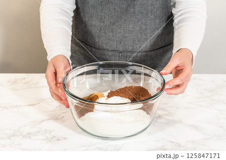 Front view of a person holding a mixing bowl filled with flour and cocoa powder for Chocolate Ginger Sugar Cookie Dough, ready to be mixed into the wet ingredients. 125847171