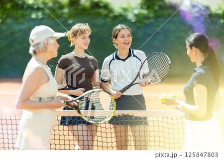 Group of women chatting on tennis court Group of women chatting on tennis court 125847803