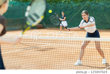 Girl plays tennis on open court with opponent Girl plays tennis on open court with opponent 125847824