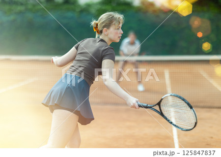 Girl plays tennis on open court with opponent 125847837