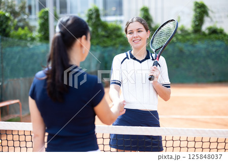 Young woman tennis player shaking hands with her opponent Young woman tennis player shaking hands with her opponent 125848037