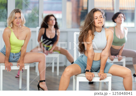 Sitting on chair, girl with long hair train to perform lap dance, interacting with imaginary partner Sitting on chair, girl with long hair train to perform lap dance, interacting with imaginary partner 125848041