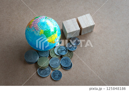 Globe with heap of coins and two square wooden blocks. 125848186