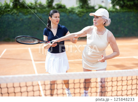 Adult woman teaches elderly woman to play tennis 125848233