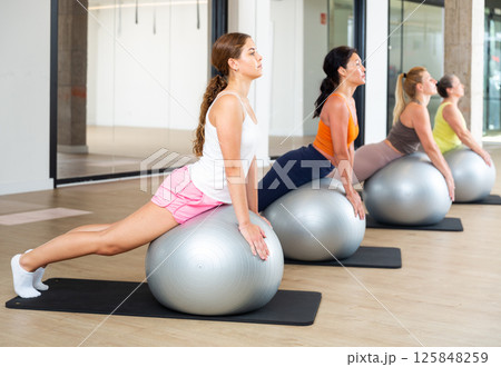 Group of women doing upward-facing dog with swiss balls Group of women doing upward-facing dog with swiss balls 125848259