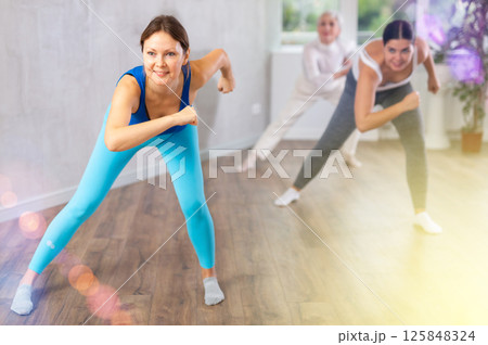 Happy women doing aerobic dances together in dance studio 125848324