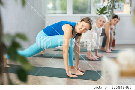 Young focused women doing stretching exercises in yoga studio 125848469