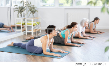 Woman stretching in seated asana Ardha Kapotasana at yoga class Woman stretching in seated asana Ardha Kapotasana at yoga class 125848497
