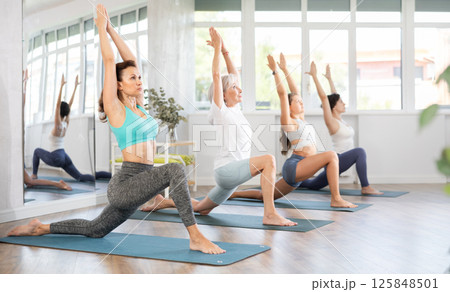 Woman performing Low Lunge Pose at group yoga session Woman performing Low Lunge Pose at group yoga session 125848501