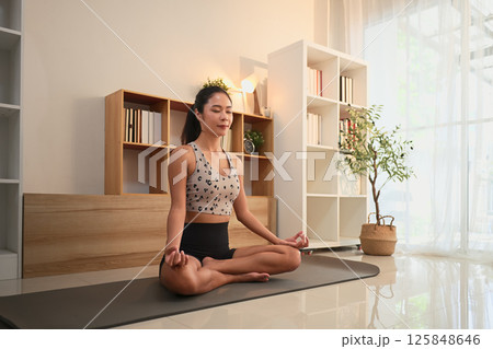 Young woman practicing yoga and mindfulness meditation in a serene home Young woman practicing yoga and mindfulness meditation in a serene home 125848646
