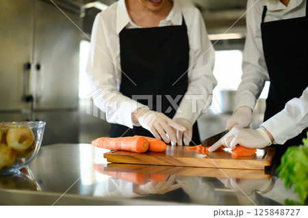 Cooking students slicing vegetables during a cooking class 125848727