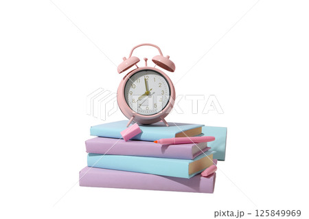 An alarm clock sits on top of stacked books, signaling study time, isolated on white An alarm clock sits on top of stacked books, signaling study time, isolated on white 125849969