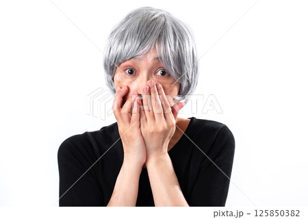 両手で口をふさぎ目を見開き驚いた表情のシニア女性 125850382