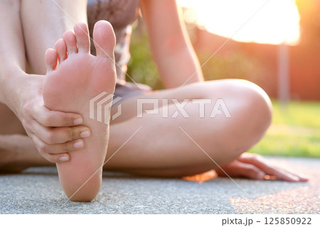 Foot pain .Woman sitting on grass Her hand caught at the foot. Having painful feet and stretching muscles fatigue To relieve pain. health concepts. 125850922