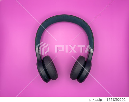 Full-size large headphones made of green plastic with soft earphones and a soft headband lie in the center of the image on a pink background one item 125850992