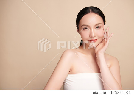 A beautiful young Asian woman with clean, fresh skin against a beige background. Skincare, facial treatment, cosmetology, beauty, and spa. An elegant portrait of an Asian woman. A beautiful young Asian woman with clean, fresh skin against a beige background. Skincare, facial treatment, cosmetology, beauty, and spa. An elegant portrait of an Asian woman. 125851106