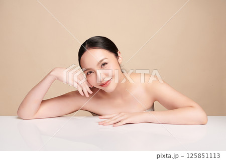 A beautiful young Asian woman with clean, fresh skin against a beige background. Skincare, facial treatment, cosmetology, beauty, and spa. An elegant portrait of an Asian woman. A beautiful young Asian woman with clean, fresh skin against a beige background. Skincare, facial treatment, cosmetology, beauty, and spa. An elegant portrait of an Asian woman. 125851113