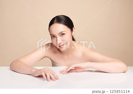 A beautiful young Asian woman with clean, fresh skin against a beige background. Skincare, facial treatment, cosmetology, beauty, and spa. An elegant portrait of an Asian woman. A beautiful young Asian woman with clean, fresh skin against a beige background. Skincare, facial treatment, cosmetology, beauty, and spa. An elegant portrait of an Asian woman. 125851114