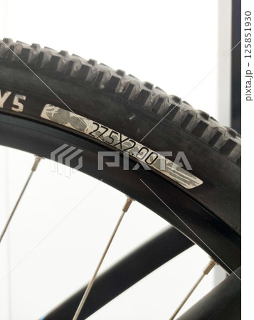 Close-up view of a mountain bike tire showcasing tread pattern, size markings, and durable rubber composition 125851930