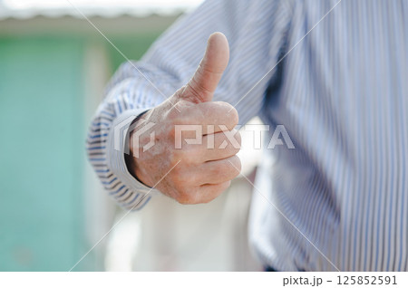 The shabby hands of a man with a finger up. The trembling hands of an old man show satisfaction. 125852591