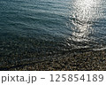 陽の光が反射する波打ち際 125854189