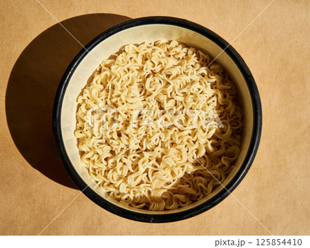 Cooked instant noodles served on ceramic plate over brown background 125854410