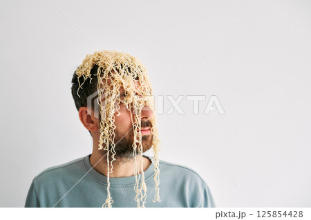 Funny man with cooked instant noodles on head 125854428