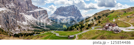 Majestic mountain panorama with winding road and snow-capped peaks in scenic landscape near Valley of Funes at Dolomites, Italy 125854486