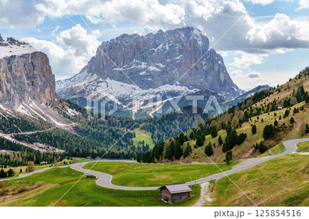 Majestic mountain landscape with alpine road and wooden cabin in spring near Valley of Funes at Dolomites, Italy 125854516