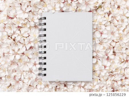 Gray blank spiral notebook over white cherry flowers top view, spring wedding mockup 125856229