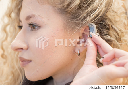 Young Caucasian woman putting on hearing aid.  125856537