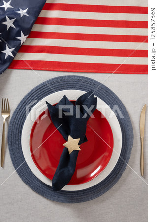 Table setting for USA Independence Day. Festive dinner with red plate and decoration in USA national flag colors and star. Vertical. View from above 125857369