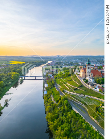 An aerial view captures Melnik City and its chateau perched above the Labe River in Czechia during sunset. The landscape showcases lush greenery and the serene river. An aerial view captures Melnik City and its chateau perched above the Labe River in Czechia during sunset. The landscape showcases lush greenery and the serene river. 125857494