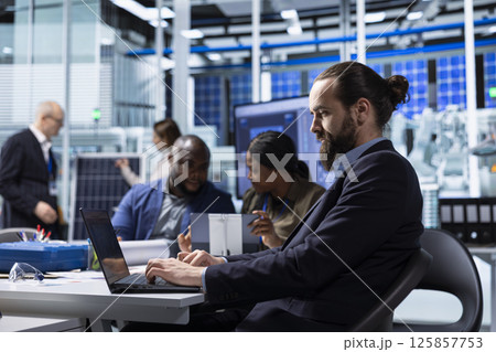 Factory scientists doing research and development, working on manufacturing automation advancements. Industrial plant experts analyze technical data during meeting, doing strategic production planning 125857753